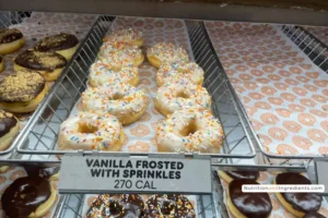 Display of Dunkin' vanilla frosted donuts with rainbow sprinkles.