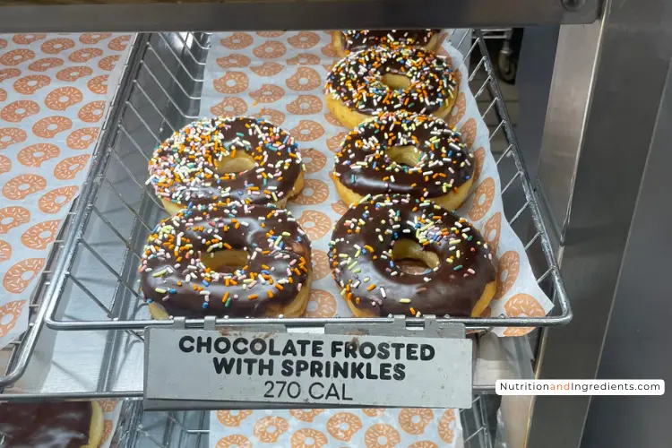 Display of Dunkin' chocolate frosted donuts with rainbow sprinkles.