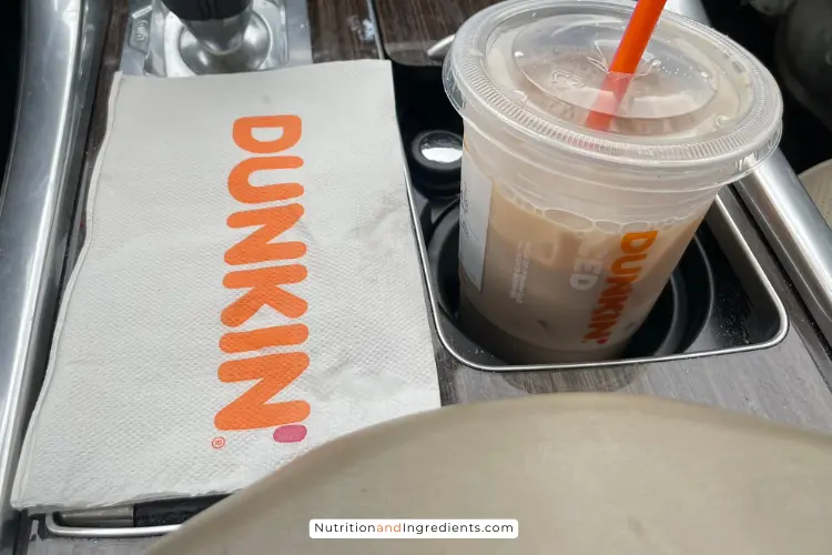 Small Dunkin' iced chai latte in cup holder.