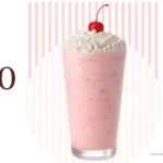 Glass filled with Chick-fil-A peppermint milkshake, whipped cream, and cherry.